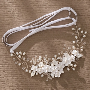 Detail of bridal headband with ceramic flowers, pearls, and crystals on a white ribbon