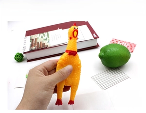 Detailed view of hand squeezing soft yellow rubber screaming chicken toy for stress relief