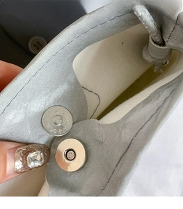 Close-up of high-quality magnetic snap closure on light gray matte leather crossbody bag