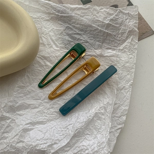 Detailed view of colorful hollow triangle and rectangular hair clips on textured paper