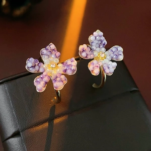 Detailed close-up of vintage flower earrings with purple beads and crystals on a display
