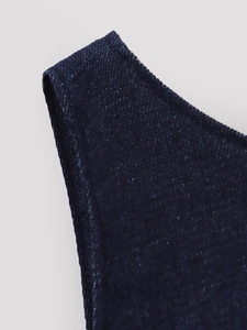Gros plan du tissu denim bleu foncé montrant le tissage détaillé et la couture du col