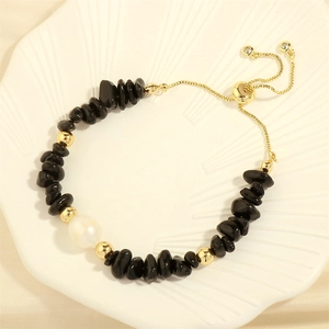 Detail of adjustable gold slider clasp with black stone chips and freshwater pearl