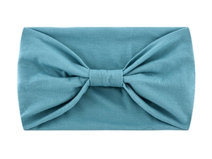 Detailed view of teal knotted headband with soft fabric texture on white background