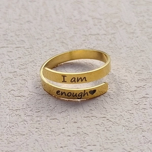 Close-up of golden stainless steel wrap ring featuring I am enough engraved text and heart