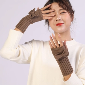 Detail of brown knitted fingerless gloves featuring a cute bow and ribbed cuffs