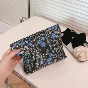 Close-up of black fabric makeup bag with blue and white floral embroidery details