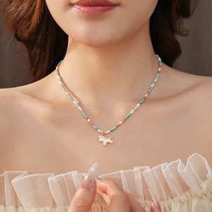 Close-up of beaded unicorn pendant necklace with colorful stones on female model neckline