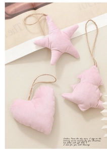 Decorazioni natalizie in velluto rosa a forma di stella, cuore e albero su fondo beige