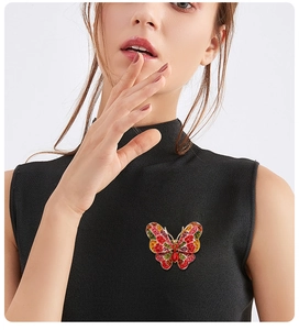 Macro detail of butterfly brooch with red, yellow, and green crystals on black garment