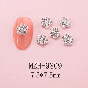 Macro detail of 7.5mm flower nail charms with sparkling crystals on pink base