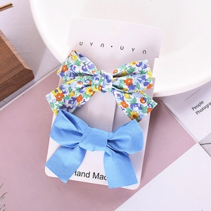 Floral and solid blue fabric bow hair clips set displayed on a stylish pink tabletop