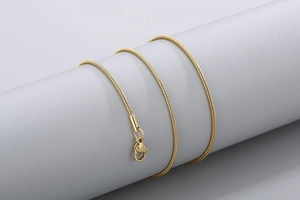 Detail shot of golden 18k plated snake chain necklace with texture and lobster clasp