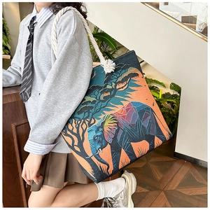 Detail of embroidered elephant canvas tote bag with thick cotton rope handles shown on shoulder