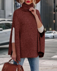Dettaglio del maglione a poncho in maglia a collo alto rosso ruggine con spacco