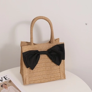 Beige straw woven handbag with large black bow decoration for beach holiday style