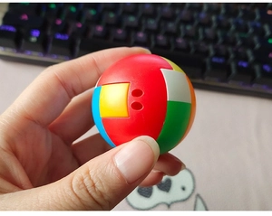 Close-up of a colorful spherical plastic puzzle toy being held, showing multi-colored slots