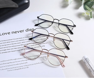 Three metal round glasses frames in black, gold, and rose gold on a stylish white setup
