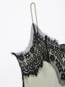 Detailed close-up of black floral lace trim on sage green satin camisole dress neck