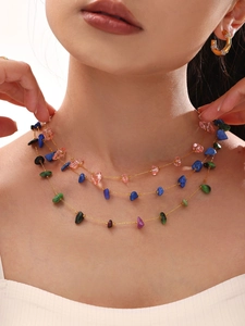 Detail van een drielaagse gouden ketting met levendige kleurrijke natuurlijke grillige stenen