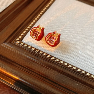 Makroaufnahme von Vintage-Granatapfel-Ohrringen mit roter Emaille und goldener Zirkonia