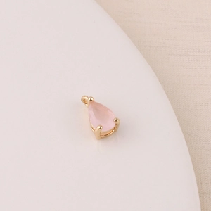 Macro shot of a pink teardrop zircon charm with gold-plated setting for DIY jewelry making