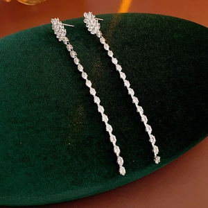 Macro shot of silver tassel earrings with zircon oval chain on velvet display