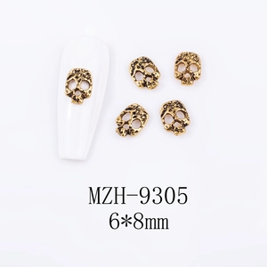 Detailed view of vintage gold skull nail charms on white base measuring 6x8mm