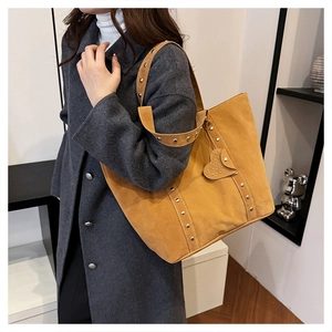Detail of brown faux suede tote bag with studded shoulder straps and heart charm