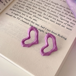 Detailed view of matte purple twisted heart earrings on an open book background