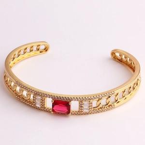 Detail of gold-tone chain link open bangle with a square red stone and clear zircons