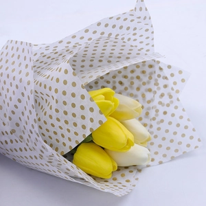 White silk tissue paper with gold polka dots wrapping yellow and white tulips