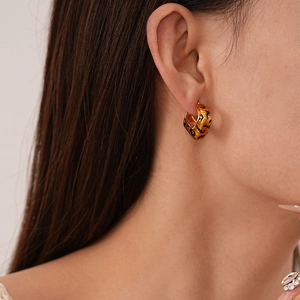 Close-up of elegant gold leopard print C-shaped earring worn by a model for a stylish look