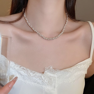 Detail of elegant pearl and rhinestone necklace set on model collarbone with lace