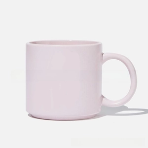 Close-up of the smooth pink ceramic mug featuring a round ergonomic handle and sturdy base