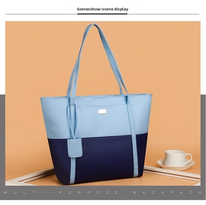 Detail of blue two-tone PU leather tote bag with metallic plaque and fine straps