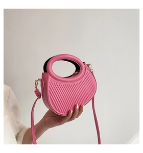Pink crescent moon bag with wavy embossed texture and gold-plated hardware in a hand-held pose