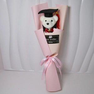 Close-up of white graduation teddy bear in pink bouquet wrap with Best Wishes tag