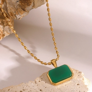 Detailed view of a gold beaded chain necklace with a rectangular green stone pendant