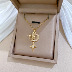 Macro shot of gold D-letter star pendant with diamonds on silk fabric gift box