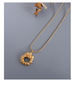 Detailed view of golden irregular lava texture ring pendant on fine snake chain necklace