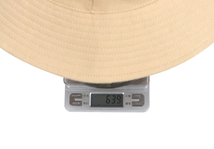 Weight measurement of a beige cotton sun hat showing 63.9g on a digital scale