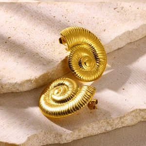 Detail of gold flower earrings with spiral shell texture on natural stone background