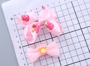 Detailed view of pink ribbon hair clips with strawberry and mushroom patterns on a ruler mat