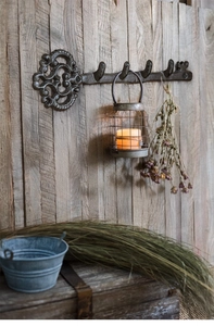Vintage key-shaped cast iron wall hook with four hangers on a rustic wooden background