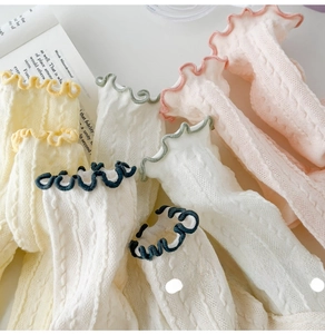 Detail of ruffle cuffs and cable knit texture on pastel breathable cotton socks