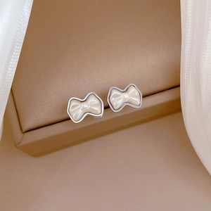 Elegant bow-shaped titanium steel stud earrings with creamy pearl finish for women