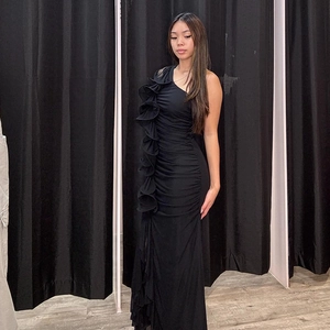 Détail d'une élégante robe de soirée noire asymétrique avec volant latéral et fente haute
