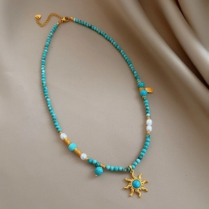 Collier ethnique avec perles turquoise et pendentif soleil doré sur tissu en satin