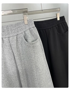 Close-up of wide elastic waistband and side pocket details on grey cotton trousers